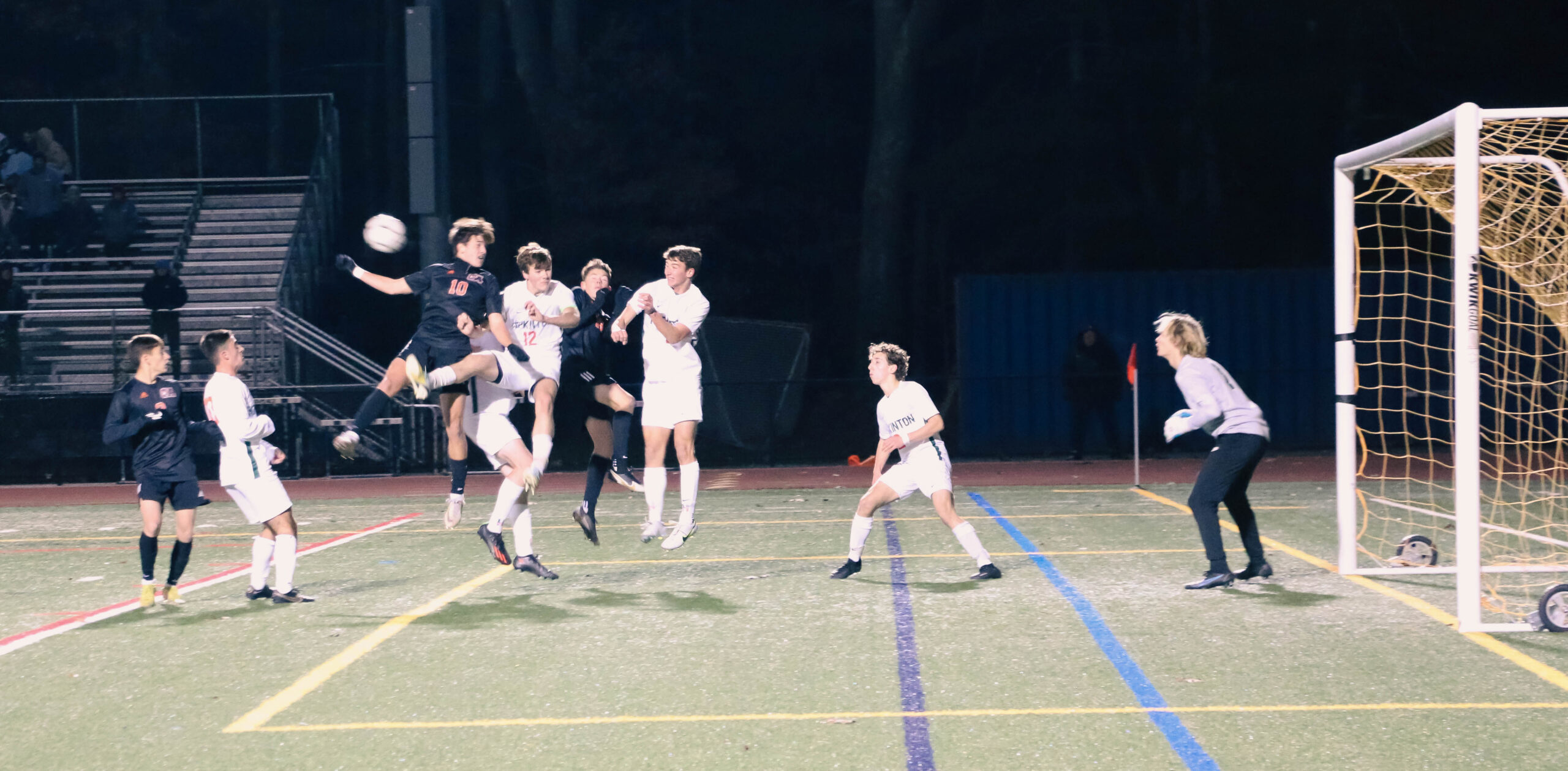 Declan Mick leaps for the header against Oliver Ames forward