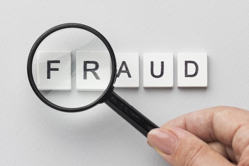 Magnifying glass highlighting the word, FRAUD.