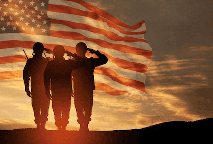 Warfighters standing at attention in front of an American Flag