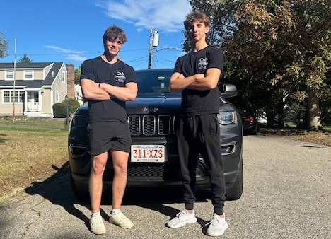 two young men standing in front of a truck