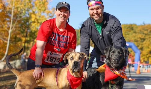 Two people with their two dogs, ready to run a 5K