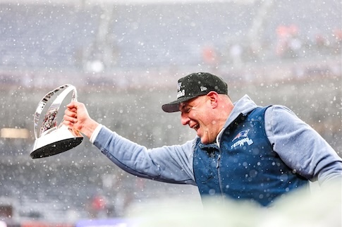 Coach Mike Vrabel holding the AFC Championship Lamar Hunt Trophy.
